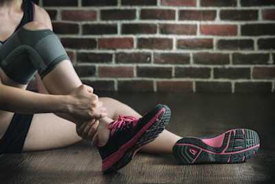 An athlete holds their injured ankle.