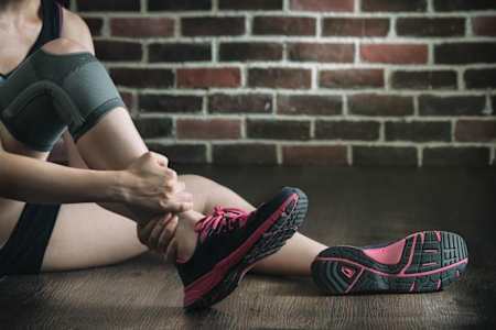 Una deportista se agarra su tobillo lesionado.