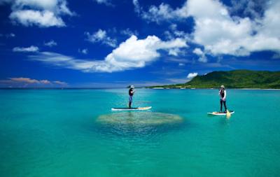 Two people use SUP boards on the waters off Ishigaki Island in Japan.