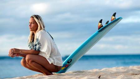 Lisa Andersen sits at the beach with her surfboard