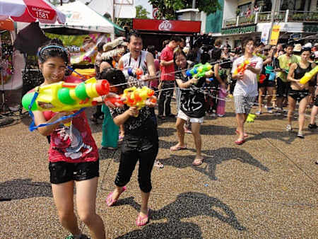 People having a water fight in the street.