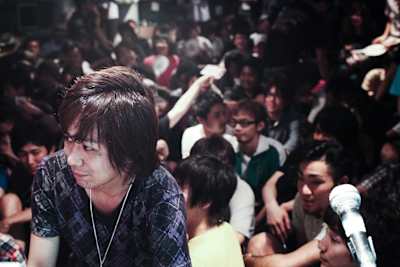 Street Fighter pro Naoto Sako participates in a tournament at a crowded Japanese arcade.