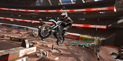 Screenshot aus MX vs ATV Legends zeigt zwei Motocross-Bikes, die im Stadion über eine Sprungschanze fliegen