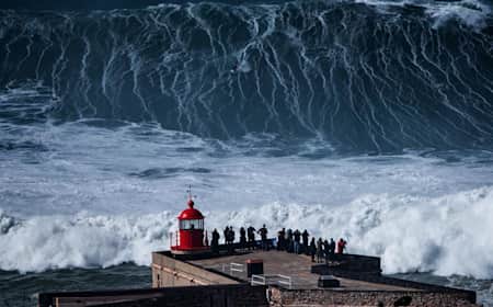 A surfer drops down the face of a huge wave at Nazare, Portugal