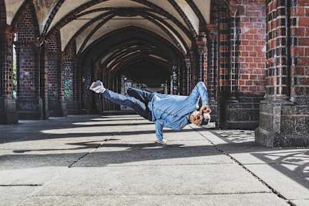 Roxrite posa apoyado sobre una mano, tocándose la gorra con su otra mano.
