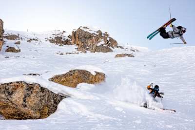 Max Palm réalise une figure en ski freestyle pendant que Manon Loschi trace dans la poudreuse aux Arcs, station emblématique des Alpes françaises.