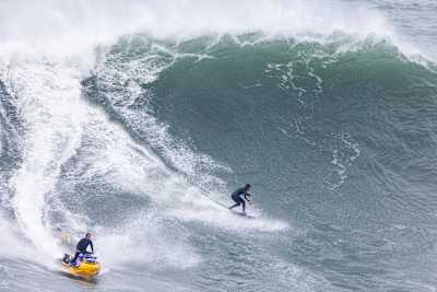 Lucas Chumbo surfando e Kai Lenny no jet ski em Nazaré, Portugal, em 15 de novembro de 2023.  