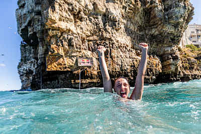 Molly Carlson of Canada raises her fists in celebration from the sea during the final Red Bull Cliff Diving World Series competition in Polignano a Mare, Italy, on 27 September 2026