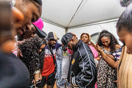 Davido (centre) is joined by his elder sister Coco Adeleke and a (literal)  circle of friends for an impromptu prayer before his performance at Afro Nation Ghana.