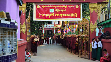 Mniši před ranní almužnou a děti čekající před branou školy