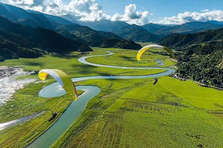 Vol en parapente au-dessus de la vallée de Pokhara au Népal, destination pour un voyage sportif.