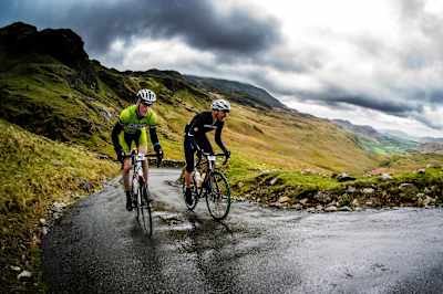 Two cyclists climbing up the ascent of the Hardknott pass.