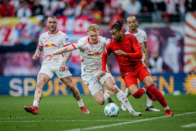 Michael Olise von Bayern München im Duell mit Nicolas Seiwald von RB Leipzig.