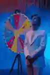 Jesper Tjäder stands next to the game-show wheel.