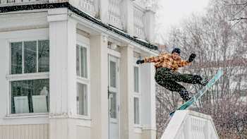 Snowboarder Eero Ettala rides a stairwell in front of a building during filming of Milestone