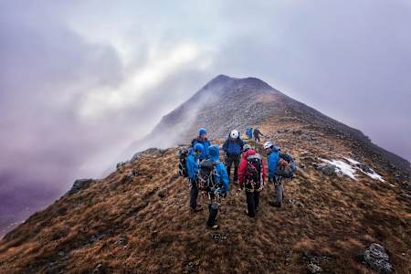 Group of climbers stood on top of mountain in foggy weather.