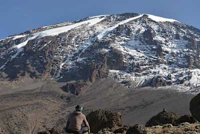 Person sits looking at Kilimanjaro Mountain.