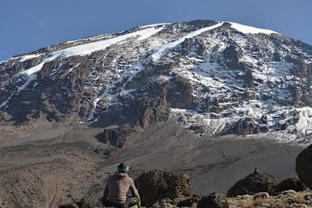 Person sits looking at Kilimanjaro Mountain.