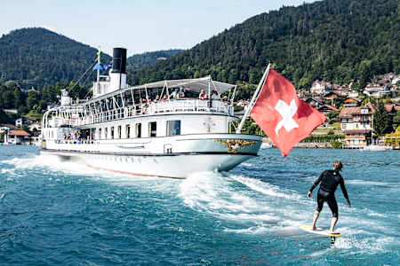 Auf dem Thunersee nutzt ein Surfer die Bugwelle eines Ausflugsschiffes.