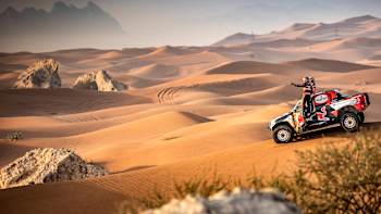Drivers survey the sand dunes from their car at the Dakar Rally.