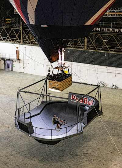Kriss Kyle riding in the Don't Look Down skatepark bowl while that is being suspended by a hot air balloon in an indoor setting.