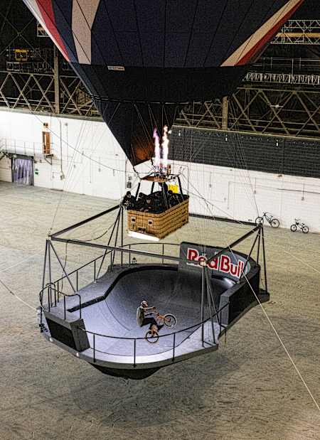 Kriss Kyle riding in the Don't Look Down skatepark bowl while that is being suspended by a hot air balloon in an indoor setting.