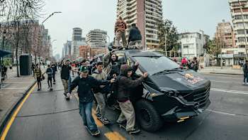 A group of skateboarders skate alongside a Red Bull van during Go Skateboarding Day in Santiago, Chile on June 21, 2022.