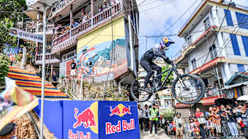 On October 26, 2024, Tomáš Slavík takes on the urban downhill course at Red Bull Tlang Raum in Aizawl, India, soaring past vibrant crowds and street art in true Red Bull style