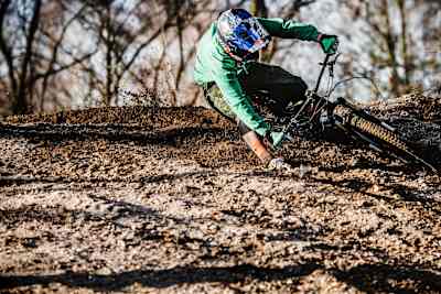 Mountain biker riders a muddy berm.