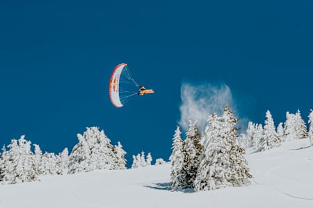 Parapente déployé et skis aux pieds, le speed rider Valentin Delluc taquine le sommet des sapins à Morzine.