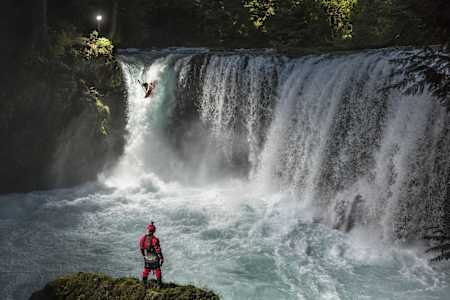 Rush Sturges standing by as a safety precaution as Rafa Ortiz drops over Spirit Falls while whitewater kayaking on the Little White Salmon river near White Salmon, Washington on May 26, 2017