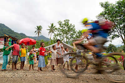 In a blur, a Spanish team mountain-bikes past a Fijian village on the third day of the grueling multisport competition.