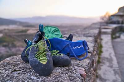 Climbing shoes and chalk bag seen on a wall.