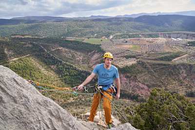 Climber stands at top of rock face ready to rappel down.