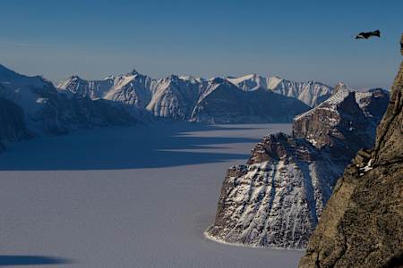 Wingsuit flier Jim Mitchell leaps from Ottawa Peak (4800ft) overlooking Sam Ford Fjord on Baffin Island.