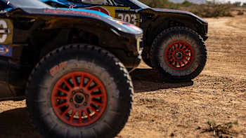 Carlos Sainz and Lucas Cruz's Raptor T1+ rally car at Rally Du Maroc 2024 in Morocco, featuring prominent Red Bull branding and large off-road tyres