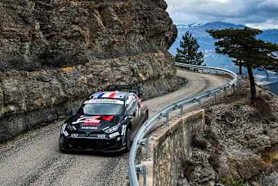 Sébastien Ogier prowadzi swoją Toyotę na zdradliwej górskiej drodze, otoczonej ośnieżonymi szczytami, podczas Rajdu Monte-Carlo, pierwszego etapu Mistrzostw Świata WRC 2025.