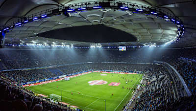Spectacular night view from the Volksparkstadion in Hamburg, Germany, where the stadium is lit up for a football match in front of thousands of spectators.