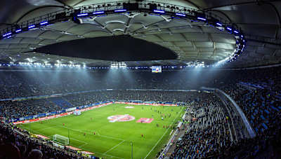 Spectacular night view from the Volksparkstadion in Hamburg, Germany, where the stadium is lit up for a football match in front of thousands of spectators.