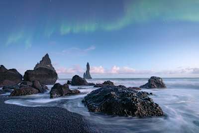 Reynisdrangar sea stack beneath the Northern Lights on Vic beach in Iceland