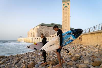 Laura Coviella and Othmane Choufani head out to surf at the base of Casablanca's Hassan II Mosque in Morocco.
