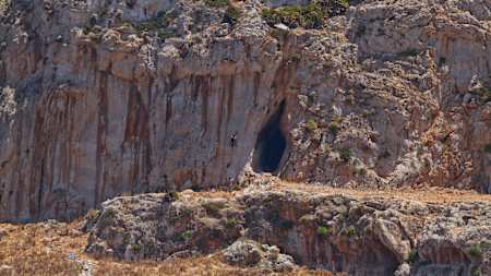 Man belays climber up craggy wall in Sicily.