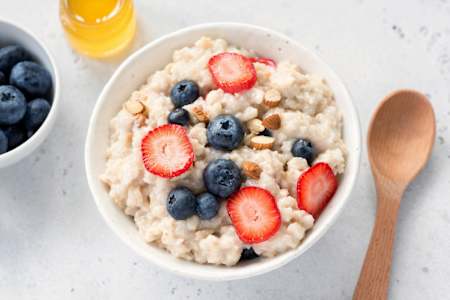Bowl of porridge topped with fruit and nuts.