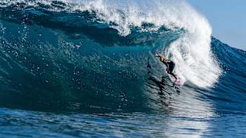 Caity Simmers surfs a wave.