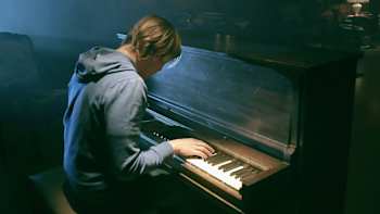 An image of a member of AWOLNATION playing a piano in the video for Sail.
