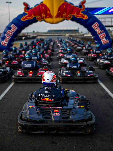 In 2026, Red Bull Racing’s Max Verstappen leads a packed karting grid beneath the Red Bull arch during Max vs 100 at Silverstone, Great Britain