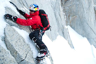David Lama free climbs a smooth rock face with snow and ice on Cerro Torre.