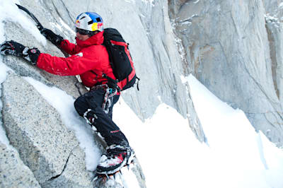 David Lama free climbs a smooth rock face with snow and ice on Cerro Torre.