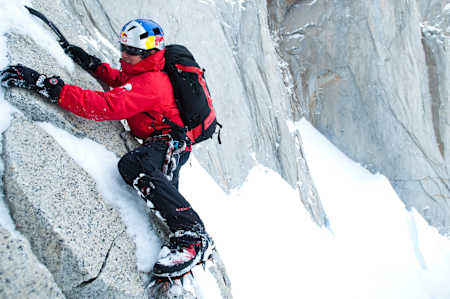 David Lama free climbs a smooth rock face with snow and ice on Cerro Torre.