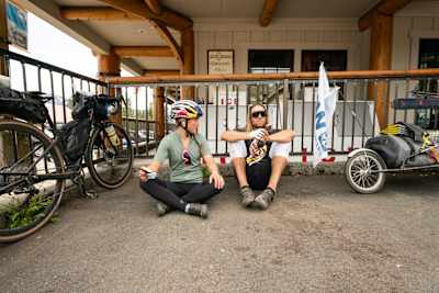 Michelle Parker and Cody Townsend sit on the floor next to their bikes at a rest stop during filming of The Mountain Why.